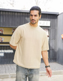 نمای نزدیک از تیشرت مردانه یقه گرد آستین کوتاه به رنگ کرم با بافت برجسته طرح کاج برای فروش عمده
