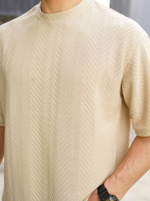 نمای نزدیک از تیشرت مردانه یقه گرد آستین کوتاه به رنگ کرم با بافت برجسته طرح کاج برای فروش عمده